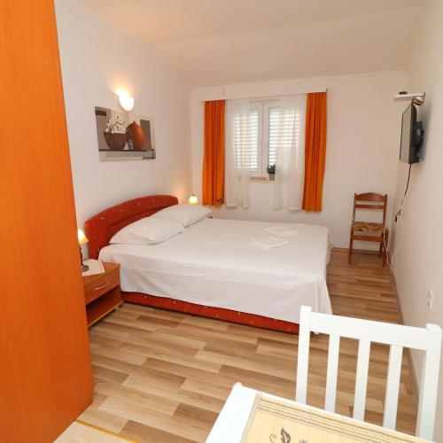 a bedroom with a white bed and a wooden floor at Apartments Sergej in Drače