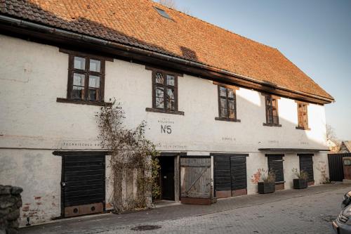 un ancien bâtiment blanc avec un toit orange dans l'établissement Noliktava No 5, à Kuldīga