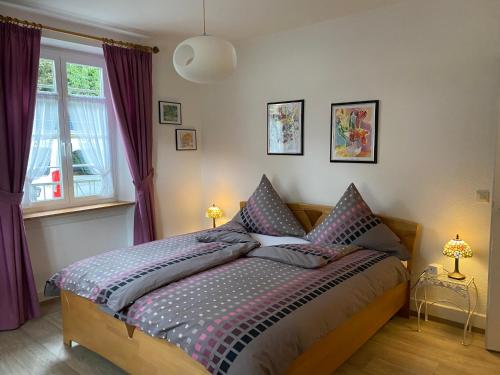 een slaapkamer met een bed met paarse gordijnen bij Haus Silberdistel in Todtmoos