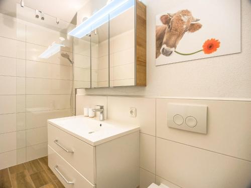 a bathroom with a sink and a picture of a cow at Ferienhaus Frühlingstraße in Sonthofen