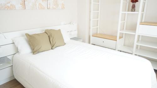 ein weißes Schlafzimmer mit einem Bett mit weißen Regalen in der Unterkunft RentalSevilla Luminoso apartamento en pleno centro in Sevilla