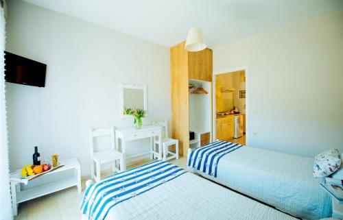 a bedroom with two beds and a desk and a mirror at Frida Apartments in Benitses