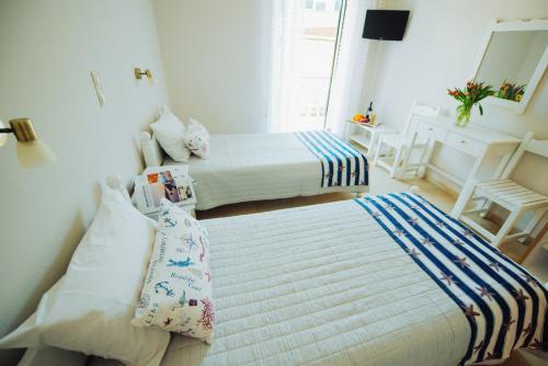 a bedroom with two beds and a table and chairs at Frida Apartments in Benitses