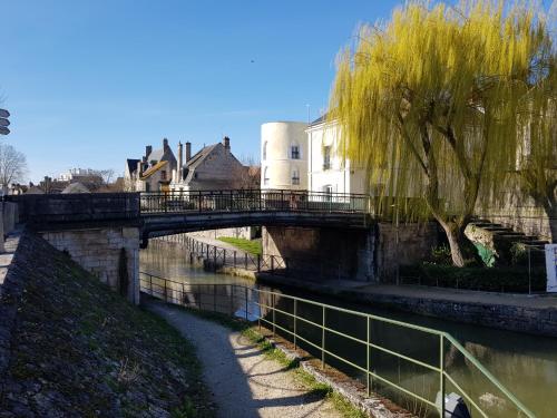 un ponte su un fiume con edifici e alberi di La maison Virginie log 1 à 2 pers charmant hyper centre parking linge wifi proximité lac canal piscine a Montargis