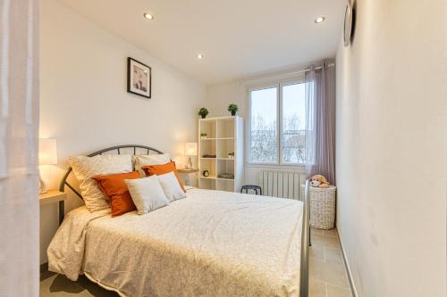 une chambre avec un lit avec des oreillers orange et une fenêtre dans l'établissement Le Petit Idéal Confort Gare Netflix Stationnement proche et gratuit, à Grenoble