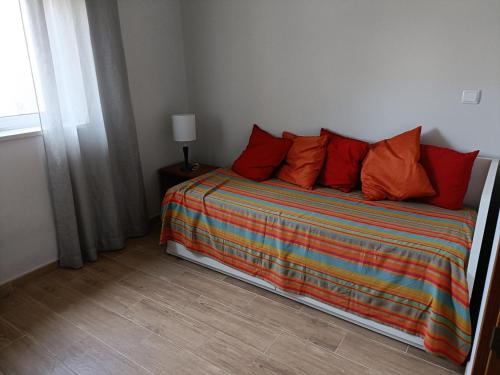 1 dormitorio con 1 cama con almohadas de color naranja y ventana en QUINTA VITAE, en Gradil