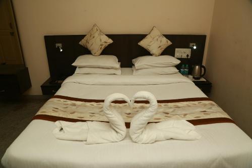 two towels on a bed with two beds at Soundarya Hotel in Bengaluru