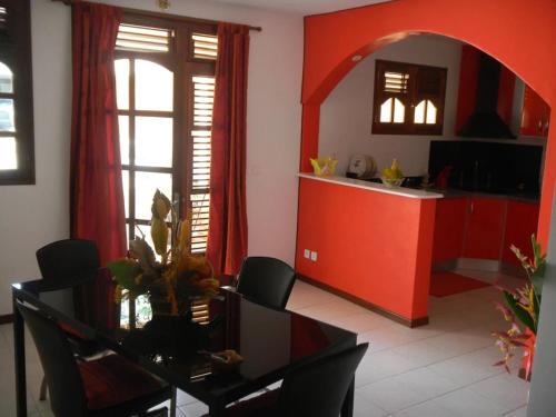 a living room with a table and a red kitchen at Villa Boat in Quartier Morne Acajou