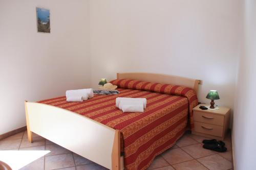 Schlafzimmer mit einem Bett mit einer roten und orangefarbenen Tagesdecke in der Unterkunft Hotel L'Ancora in Capo Vaticano