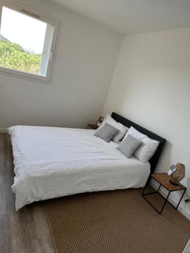 une chambre avec un grand lit blanc avec une fenêtre dans l'établissement Superbe appartement dans les calanques, à Marseille