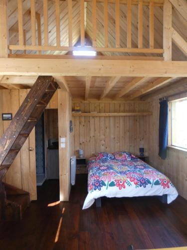 une chambre avec un lit dans une cabane en bois dans l'établissement Le chalet de la Ferme Feugère, à Barbeville