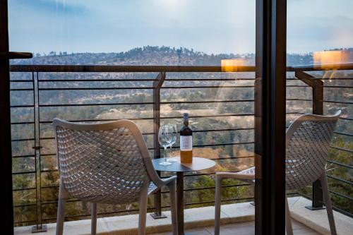 a table with a bottle of wine and two chairs on a balcony at Logos hotel in Yad Hashmona in Yad Hashmona