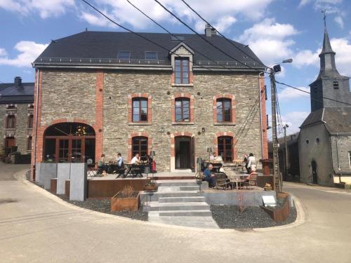 un gran edificio de ladrillo con gente sentada fuera de él en Brasserie du Simonis en Laforêt