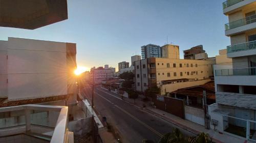 Lindo apartamento com Wi-Fi a 370m da Praia do Morro, próximo ao Marlim Azul e à Av Paris في غواراباري: شارع المدينة مع غروب الشمس خلف المباني
