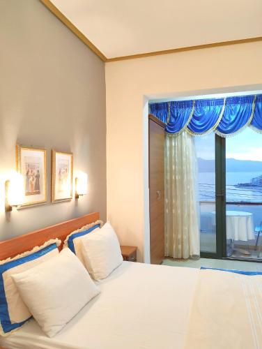 a bedroom with a bed and a large window at Olympia Hotel in Sarandë