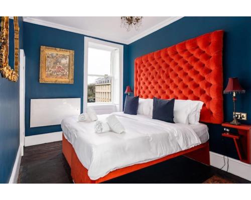 a bedroom with a large bed with a red headboard at Bennett's Lodgings a luxurious 2 bed apartment in Bath