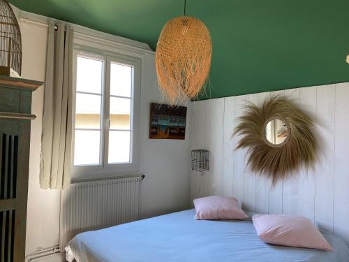 Un dormitorio con una cama con almohadas rosas y una ventana en Maison en bord de mer, en Blonville-sur-Mer