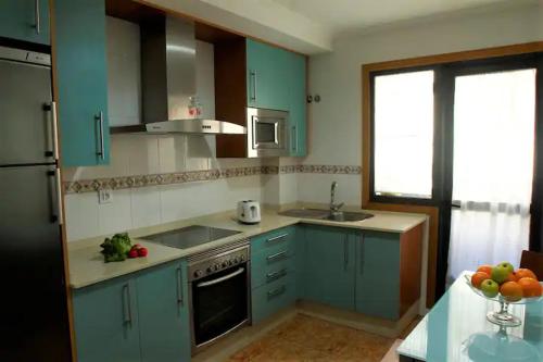 een keuken met blauwe kasten, een wastafel en een raam bij Desconectaengalicia La Perla, piscina y parking in Sanxenxo