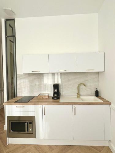 a white kitchen with a sink and a microwave at L incomparable - International Palace in Vichy