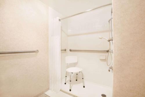 a shower with a white chair in a bathroom at Travelodge by Wyndham Pueblo in Pueblo