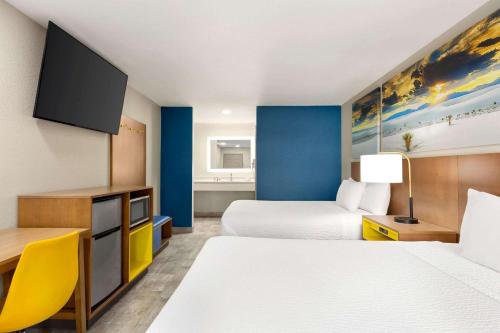 a hotel room with two beds and a flat screen tv at Days Inn by Wyndham Ruidoso Downs in Ruidoso Downs
