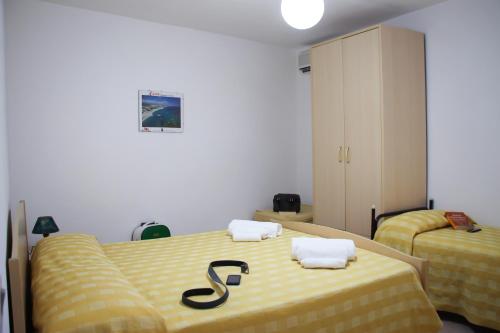 una camera con due letti con lenzuola gialle di Hotel L'Ancora a Capo Vaticano