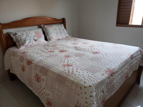 uma cama com um edredão branco e rosa e almofadas em Loft Holambra em Holambra