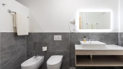 a bathroom with a sink and a toilet and a mirror at Hotel Markushof - Adults only in Ora/Auer