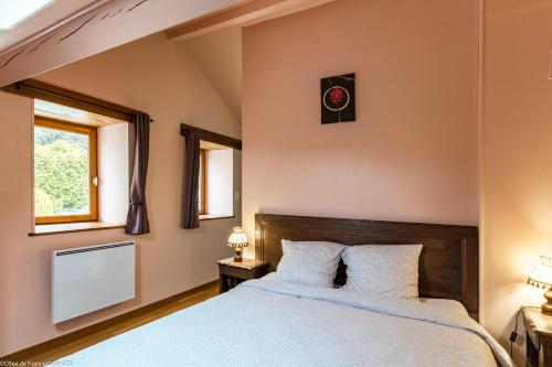 a bedroom with a large bed and two windows at La Maisonnette in Chaudenay-le-Château