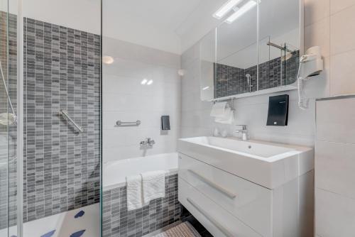 a white bathroom with a sink and a shower at Paparazzi Apartment in Split