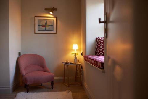 a room with a pink chair and a lamp at The Bell & Crown in Zeals