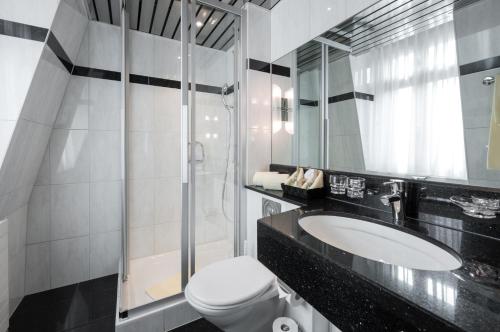 a bathroom with a sink and a toilet and a mirror at GAIA Hotel Basel - the sustainable 4 star hotel in Basel