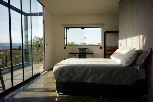 a bedroom with a bed and a large window at Casa Nuvem Lotf House + Suíte in Alto Paraíso de Goiás