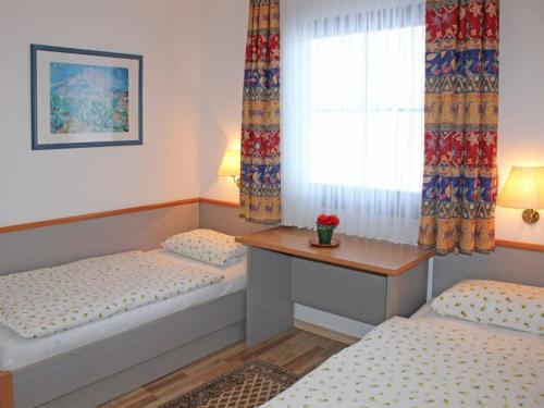 Cette chambre comprend 2 lits, une table et une fenêtre. dans l'établissement Ferienhaus Nr 48, Kategorie Komfort, Feriendorf Hochbergle, Allgäu, à Bichel