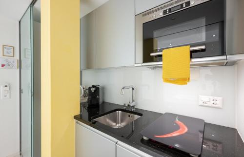 a kitchen with a sink and a microwave at GAIA Hotel Basel - the sustainable 4 star hotel in Basel
