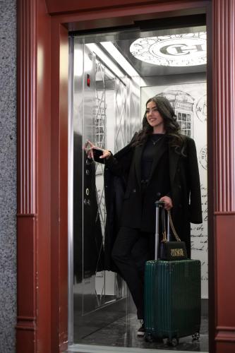 a woman is standing in a doorway with a suitcase at Central Hotel Yerevan in Yerevan