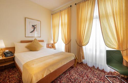 a bedroom with a bed and a desk and windows at GAIA Hotel Basel - the sustainable 4 star hotel in Basel