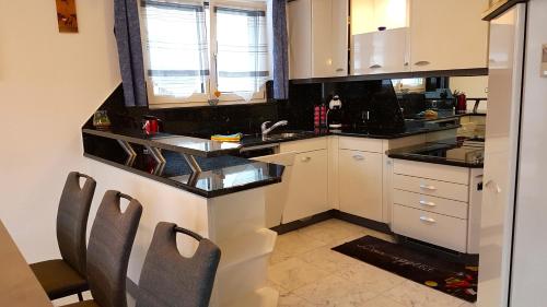 a kitchen with white cabinets and black counter tops at Appartement Lehnbach in Saas-Almagell