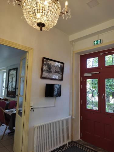 Cette chambre est dotée d'une porte rouge et d'un lustre. dans l'établissement Hotel des Voyageurs, à Rocamadour