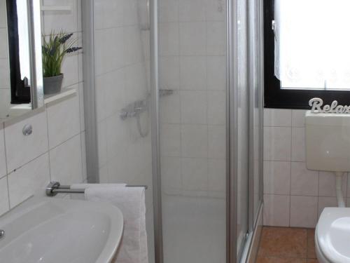 uma casa de banho branca com um chuveiro e um lavatório. em Ferienhaus Nr 12, Kategorie Komfort, Feriendorf Hochbergle, Allgäu em Bichel