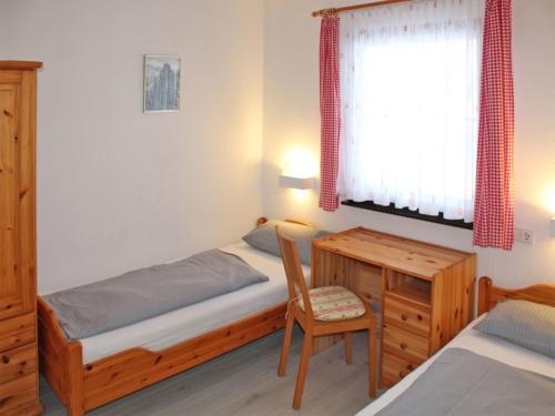 1 dormitorio con cama, escritorio y silla en Ferienhaus Nr 56, Kategorie Komfort, Feriendorf Hochbergle, Allgäu, en Bichel