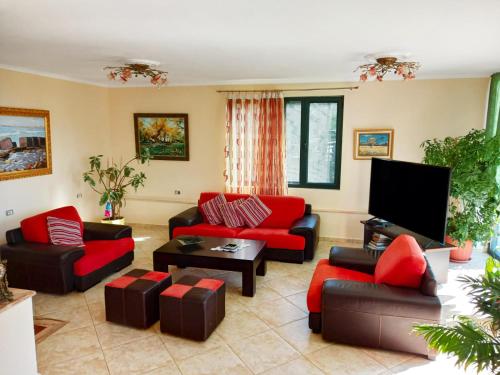 a living room with red furniture and a flat screen tv at Beach Hiking Holiday Villa Luanit in Tragjas