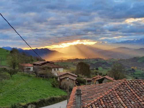 una puesta de sol sobre un pueblo con montañas en el fondo en Casa Tenada, en Robledo