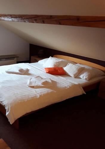 a large bed with white sheets and red pillows at Hotel Garni Belveder in Hřensko