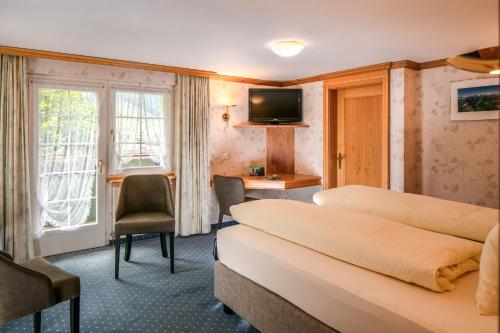 a hotel room with two beds and a desk at Hotel Alpenblick in Weissbad