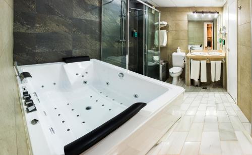 a large white tub in a bathroom with a toilet at Bellavista Sevilla in Seville