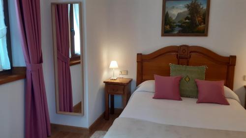 a bedroom with a bed with pink and green pillows at Apartamentos El Haya in Cosgaya