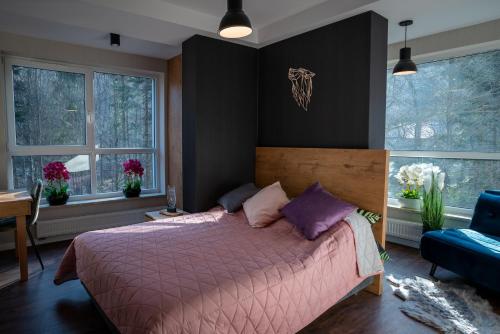 - une chambre avec un lit doté de draps violets et de fenêtres dans l'établissement Apartament Kurort Kozubnik Wilcza Wataha, à Porąbka