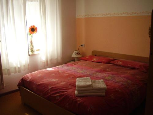 a bedroom with a red bed with towels on it at Albergo Malga Ciapela in Rocca Pietore