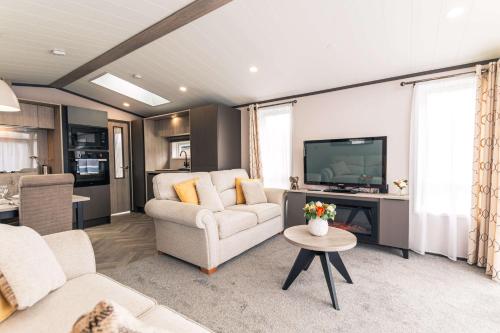 a living room with a couch and a tv at Rueben's Lodge with Hot Tub in York